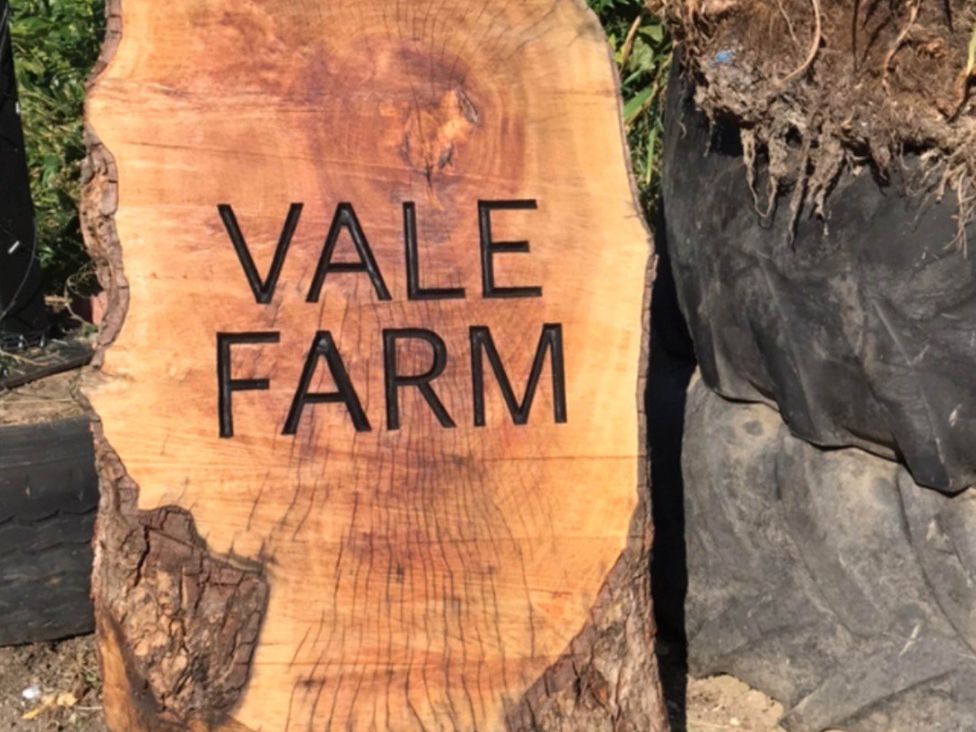 A wooden sign displaying 'VALE FARM' in an outdoor area