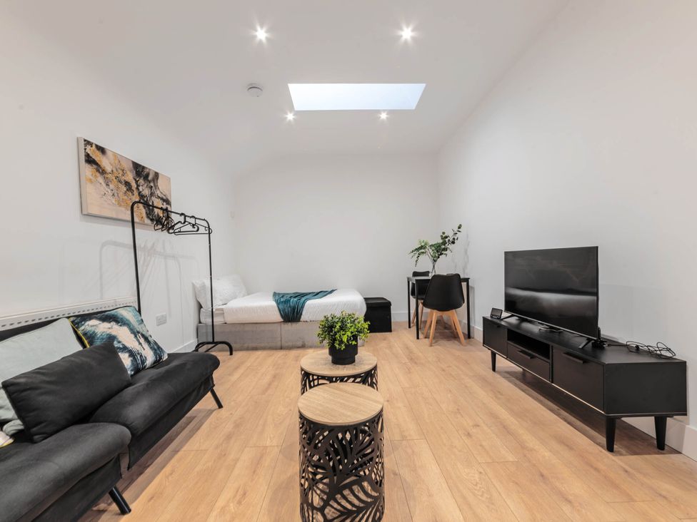 A living room with a sofa, television, and bed at Central - Sleeps 2 - Near Transport - Parking in Maidenhead