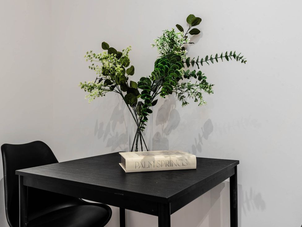A table with artificial flowers and a book at Central - Sleeps 2 - Near Transport - Parking in Maidenhead