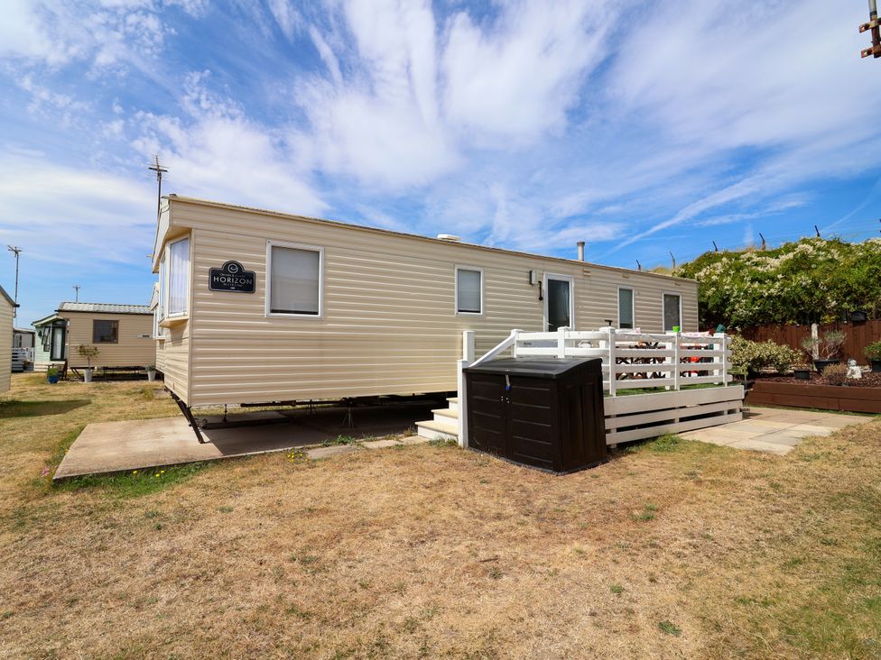 A mobile home with a deck and storage shed at Plot 594 in Prestatyn