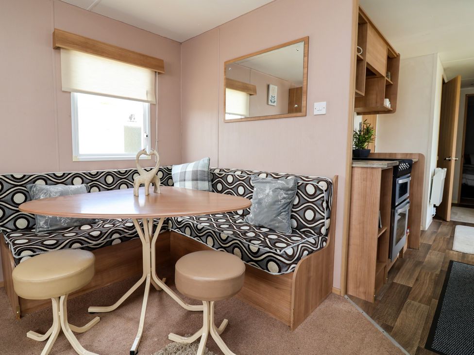 A dining area with a table and couch at Plot 594 in Prestatyn