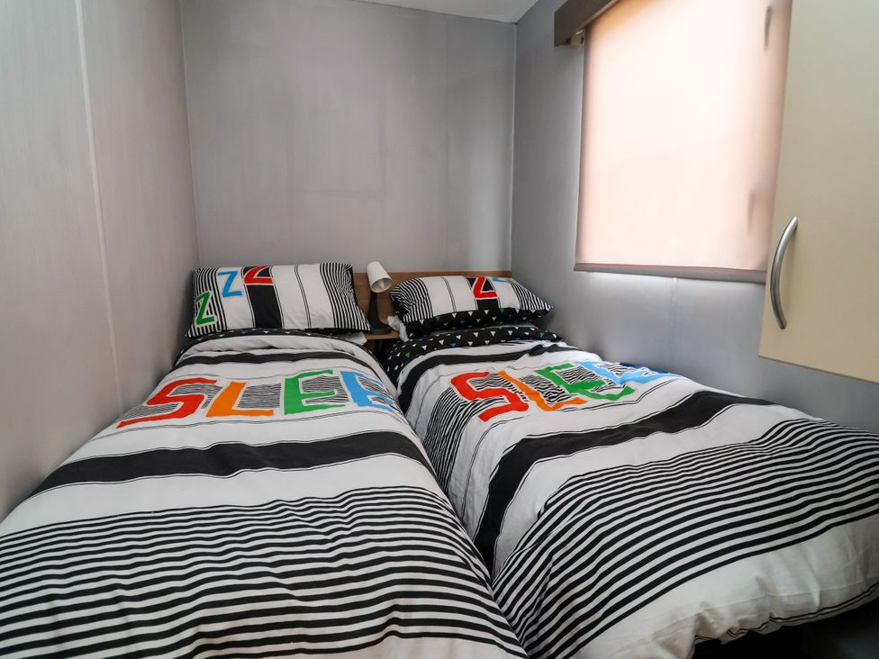 A bedroom with two beds and a cupboard at Plot 594 Prestatyn