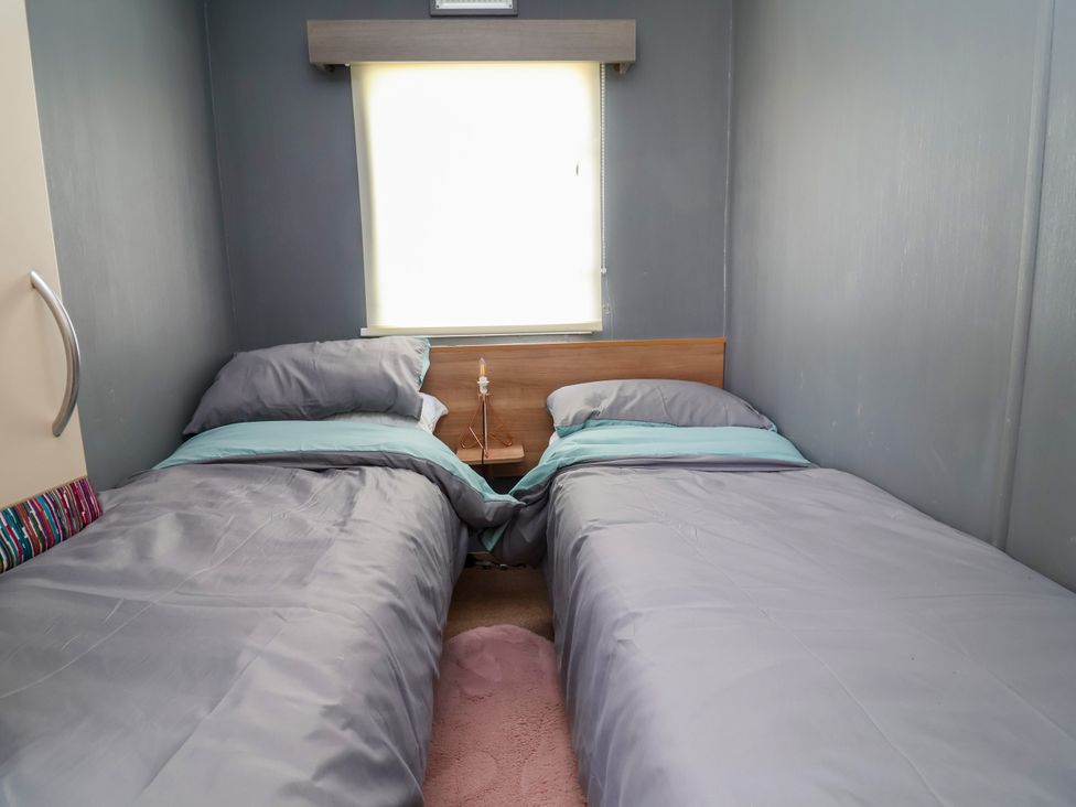 A bedroom with two single beds and a bedside table at Plot 594 in Prestatyn