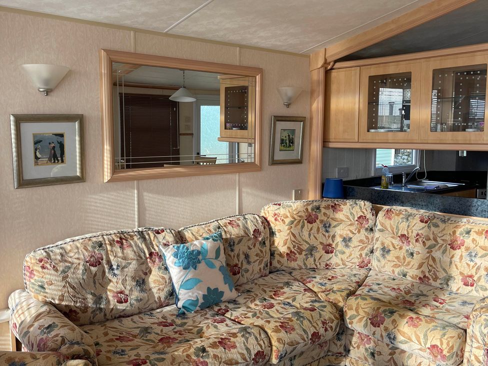A living room with a sofa and a mirror at Immaculate 2-Bed Static Caravan at Monreith