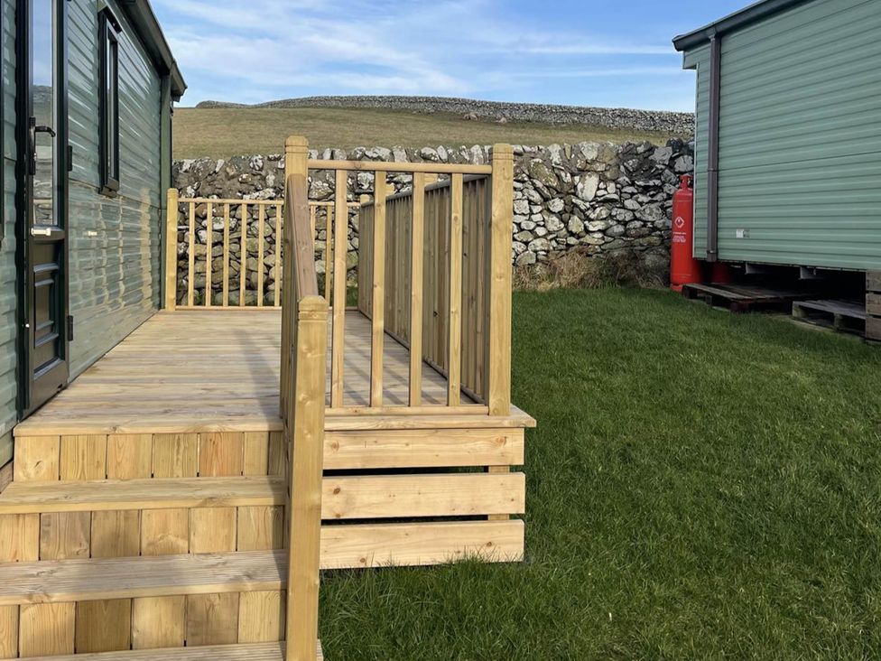 A wooden deck with railing and a door at Immaculate 2-Bed Static Caravan at Monreith near Whithorn