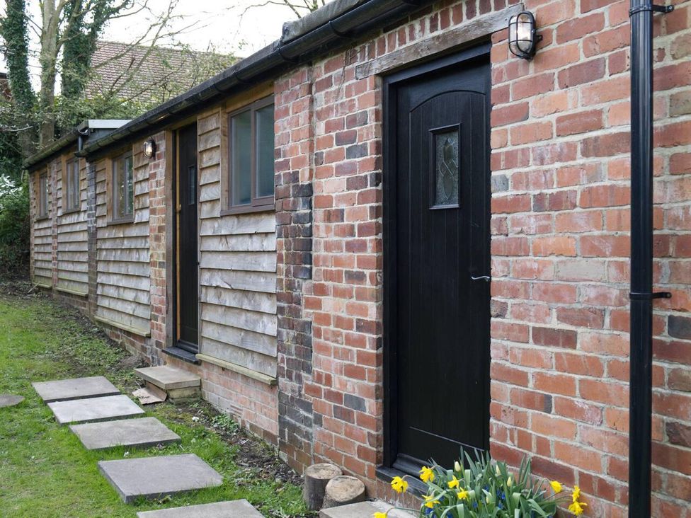 Exterior view of a cottage with a black door and pathway stones at Cottage Sleeps 2 Garden Parking in Ryton