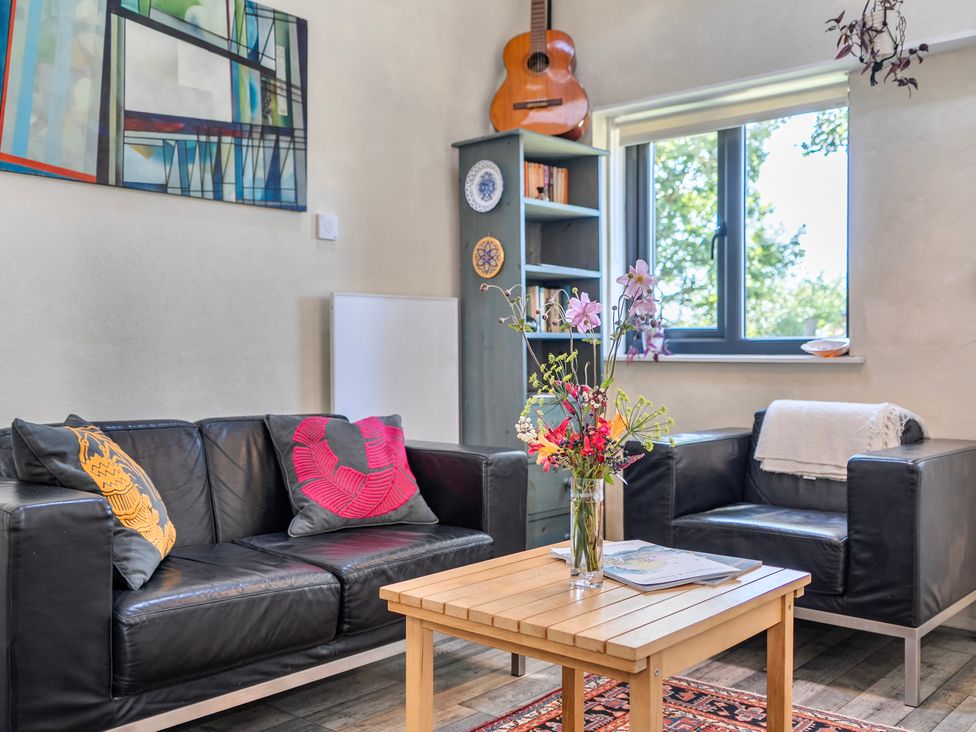 A living room with a sofa, table, bookshelf, and window at Little Linney Sleeps 2 Garden Parking Wifi Hartland