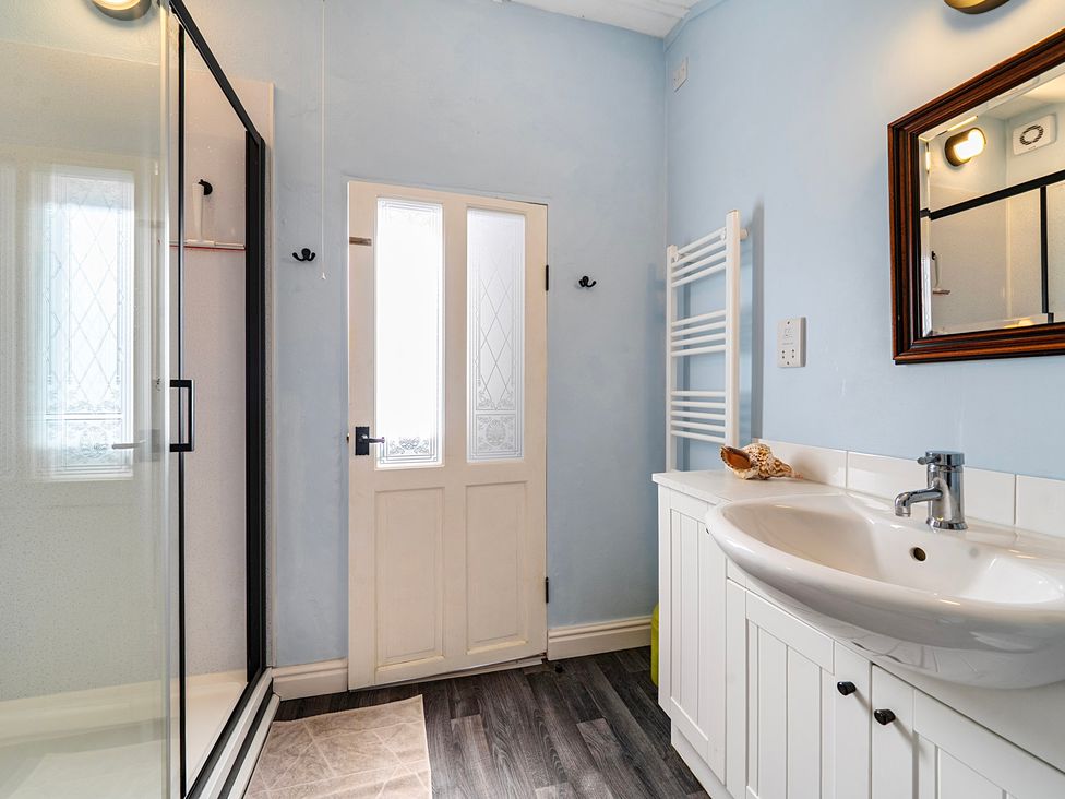 A bathroom with a shower, sink, and door at Little Linney Sleeps 2 Garden Parking Wifi Hartland