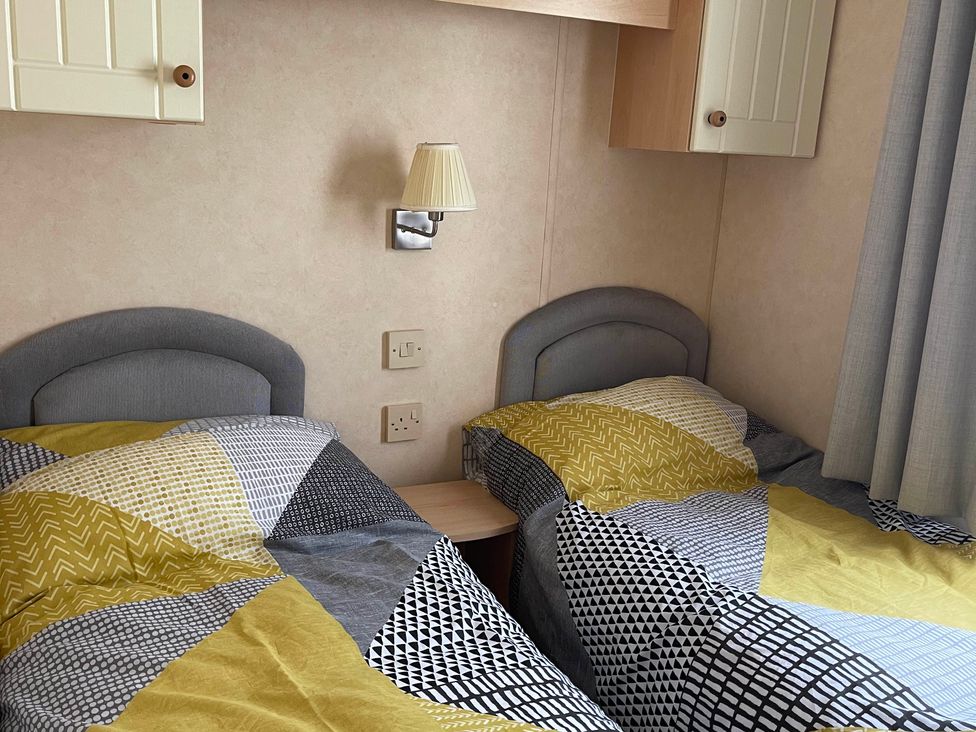 A bedroom with two single beds and a bedside lamp at Beautiful 2 Bed Static caravan