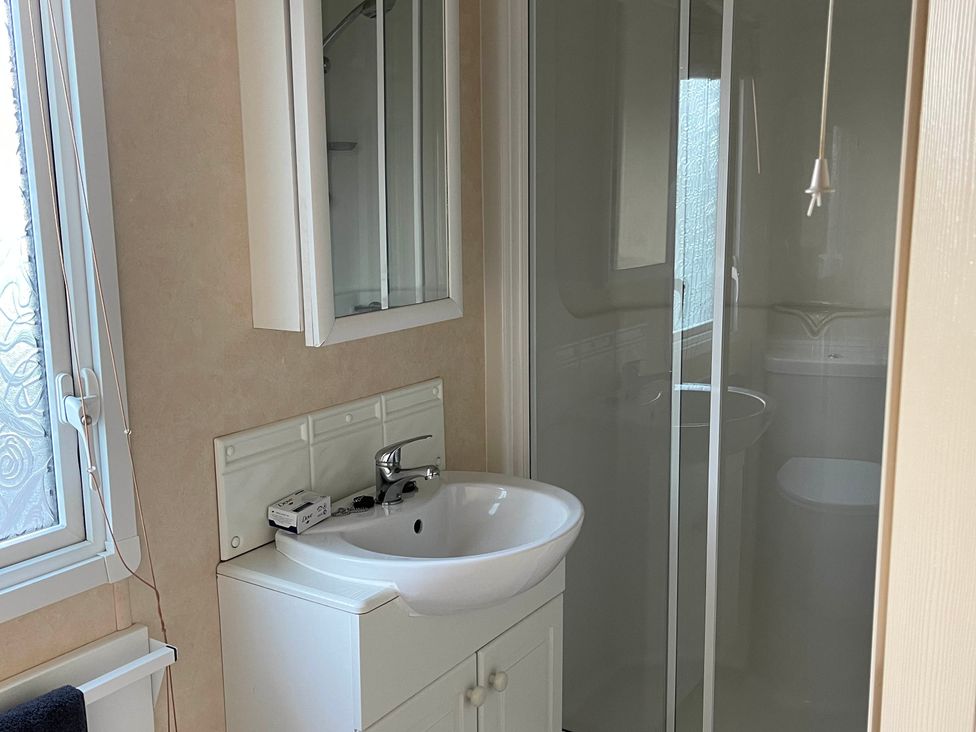 A bathroom with a sink, mirror, shower, and toilet at Beautiful 2 Bed Static caravan