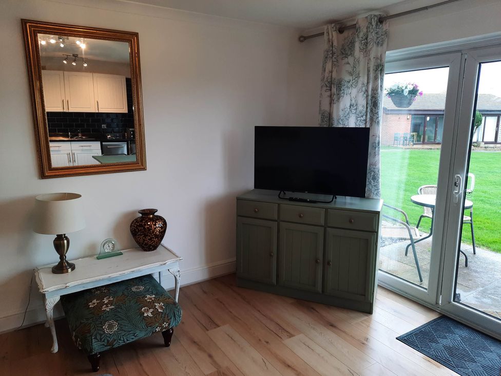 A living room with a television and a vase on a cabinet at St Margaret's 2 Bed Chalet Sleeps 4 Pets Ok