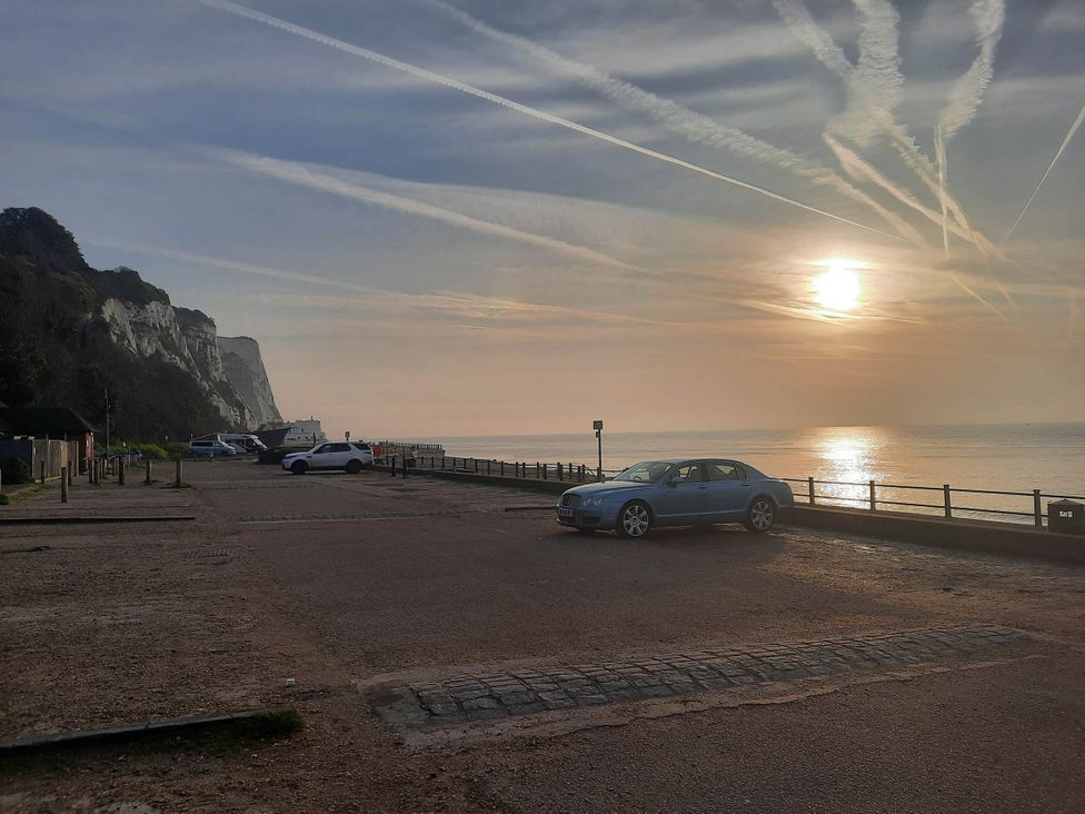 A parking lot next to a beach with a car and cliffs at St Margaret's 2 Bed Chalet Sleeps 4 Pets Ok