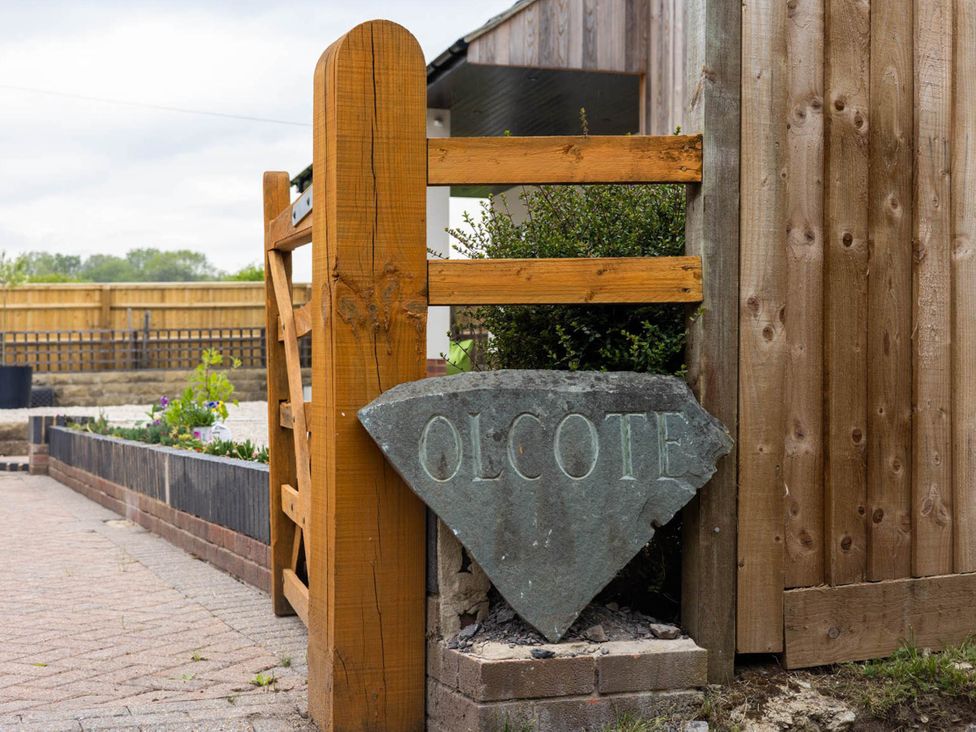 A wooden gate and stone sign at the entrance of the garden at Olcote