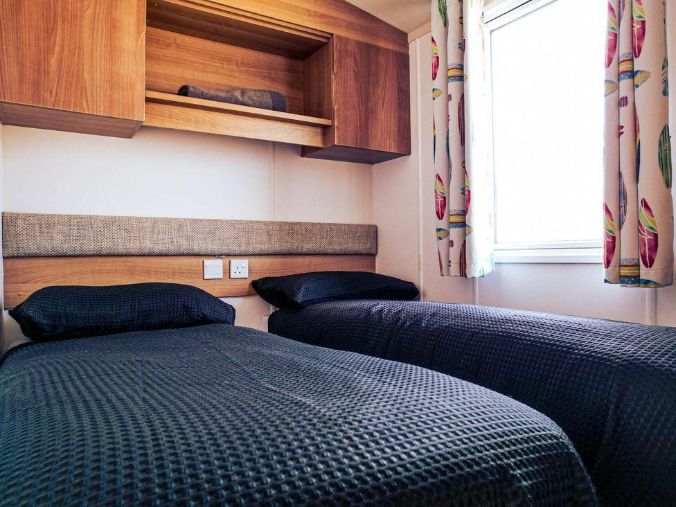 A bedroom with two beds and a shelf at Captivating 6-Person Caravan in Rhyl