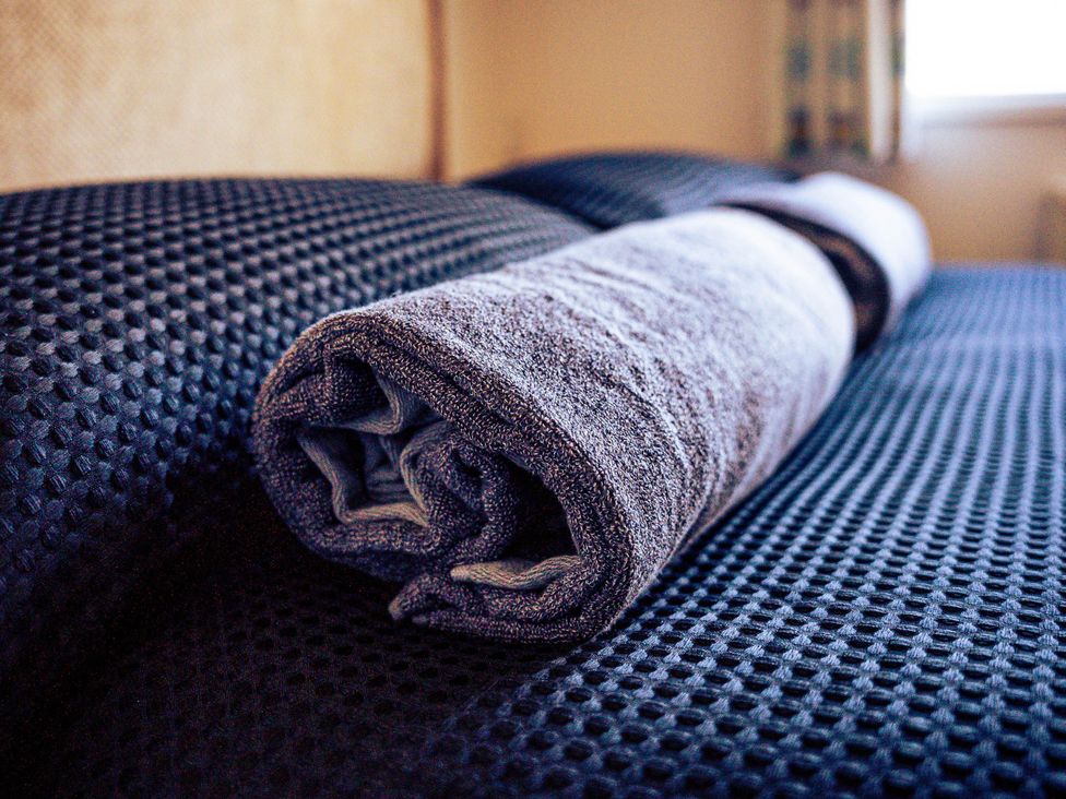 A rolled towel on bed linens at Captivating 6-Person Caravan in Rhyl