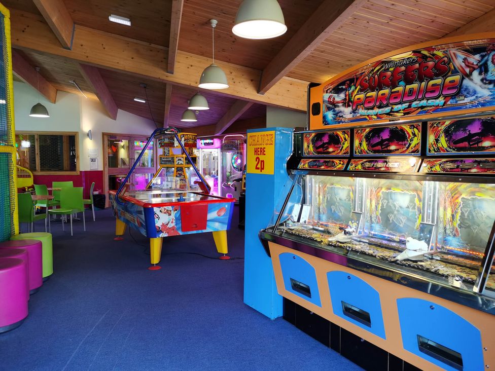 A games room with arcade machines and seating at Sea and Mountain view Sunbeach Holiday Snowdonia, Llwyngwril