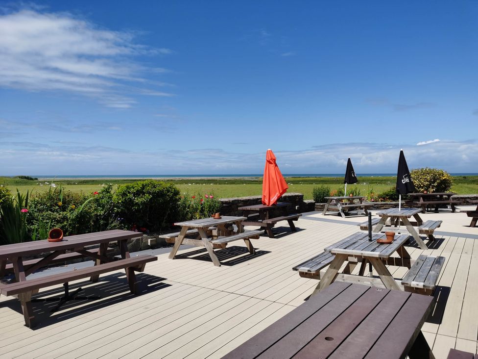 An outdoor seating area with picnic tables and umbrellas at Sea and Mountain view Sunbeach Holiday Snowdonia in Llwyngwril