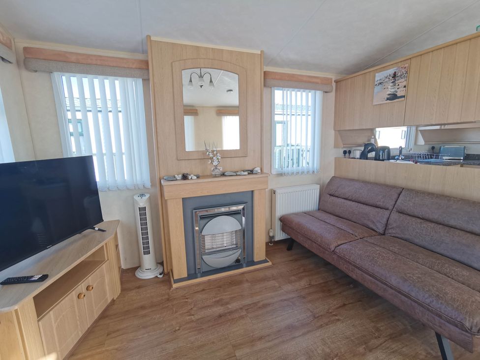 A living room with a sofa and television at Sea and Mountain view Sunbeach Holiday Snowdonia in Llwyngwril