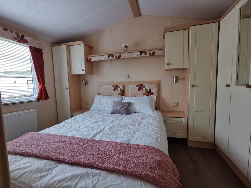 A bedroom with a double bed and storage cabinets at Sea and Mountain view Sunbeach Holiday Snowdonia Llwyngwril