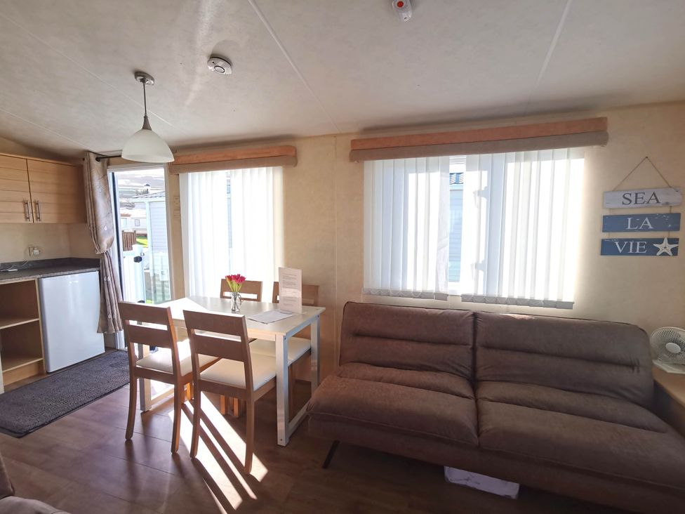 A living room with a dining area and refrigerator at Sea and Mountain view Sunbeach Holiday Snowdonia