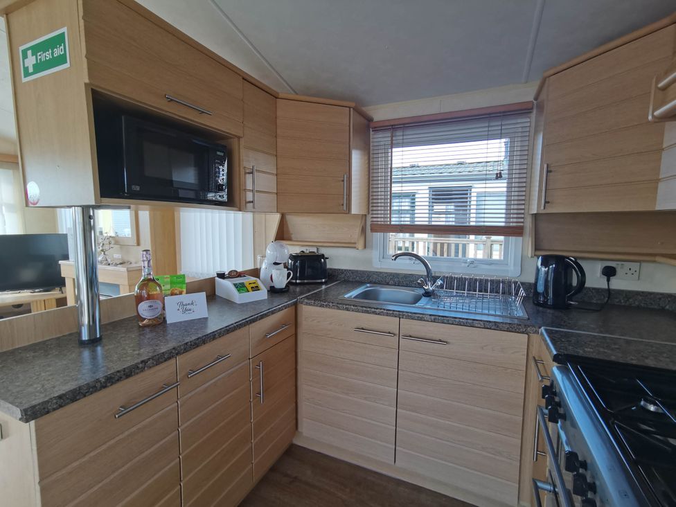 A kitchen with a microwave, kettle, and sink at Sea and Mountain view Sunbeach Holiday Snowdonia in Llwyngwril