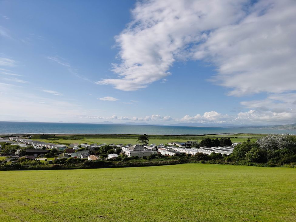 An outdoor view of the sea and green fields at Sea and Mountain view Sunbeach Holiday Snowdonia in Llwyngwril