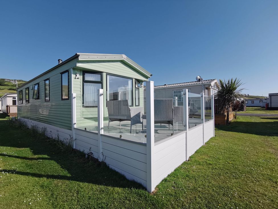A mobile home with a veranda and seating at Sea and Mountain view Sunbeach Holiday Snowdonia in Llwyngwril