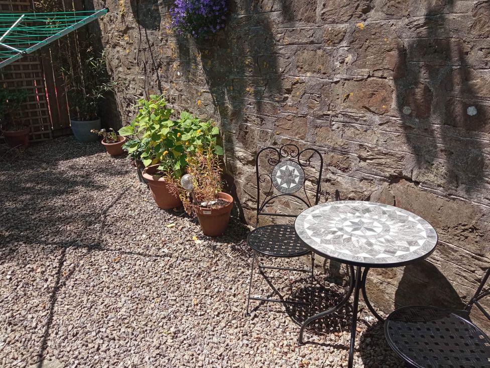 A garden with a table and chair next to potted plants at Ground Floor Cornish Retreat Free Parking Bodmin