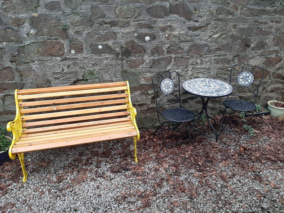 A garden with a wooden bench and a table with two chairs at Ground Floor Cornish Retreat Free Parking Bodmin