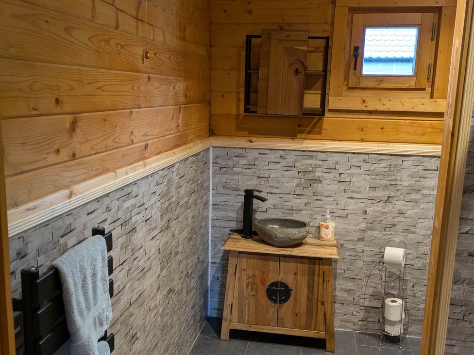 A bathroom with a sink and wooden cabinet at Pet Friendly - Lodge at Riverview Holiday Park Mangerton near Newcastleton