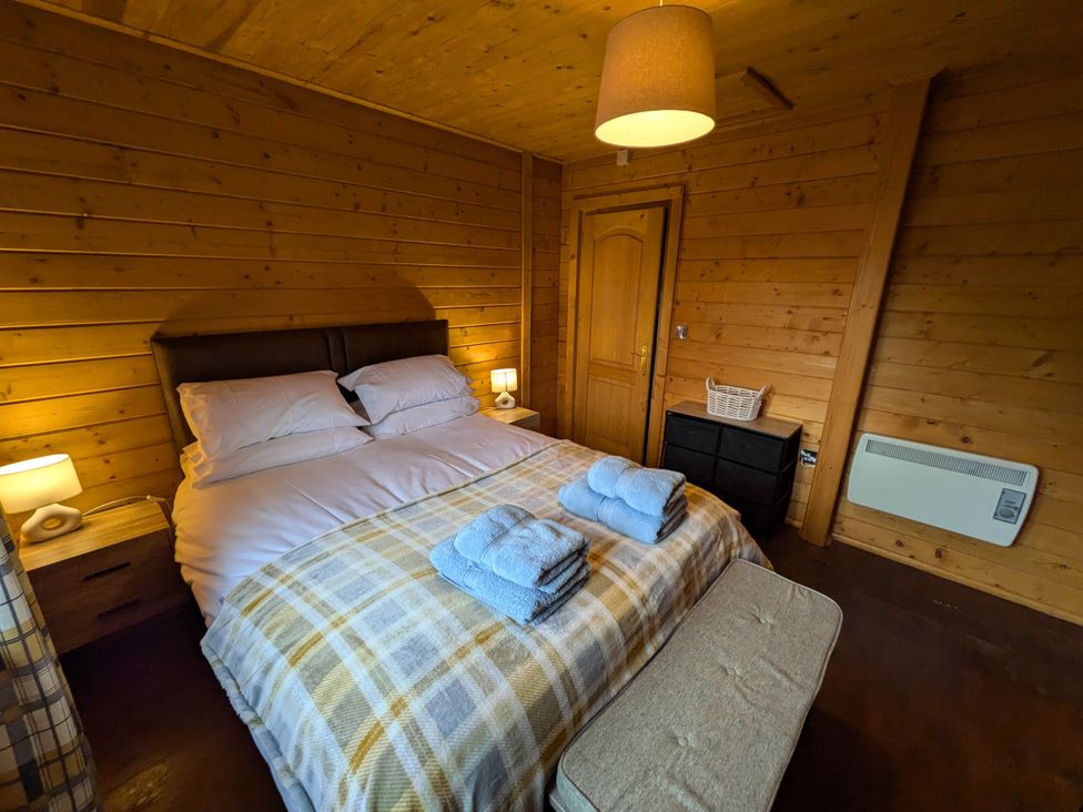 A bedroom with a double bed and bedside tables at Pet Friendly - Lodge at Riverview Holiday Park near Newcastleton