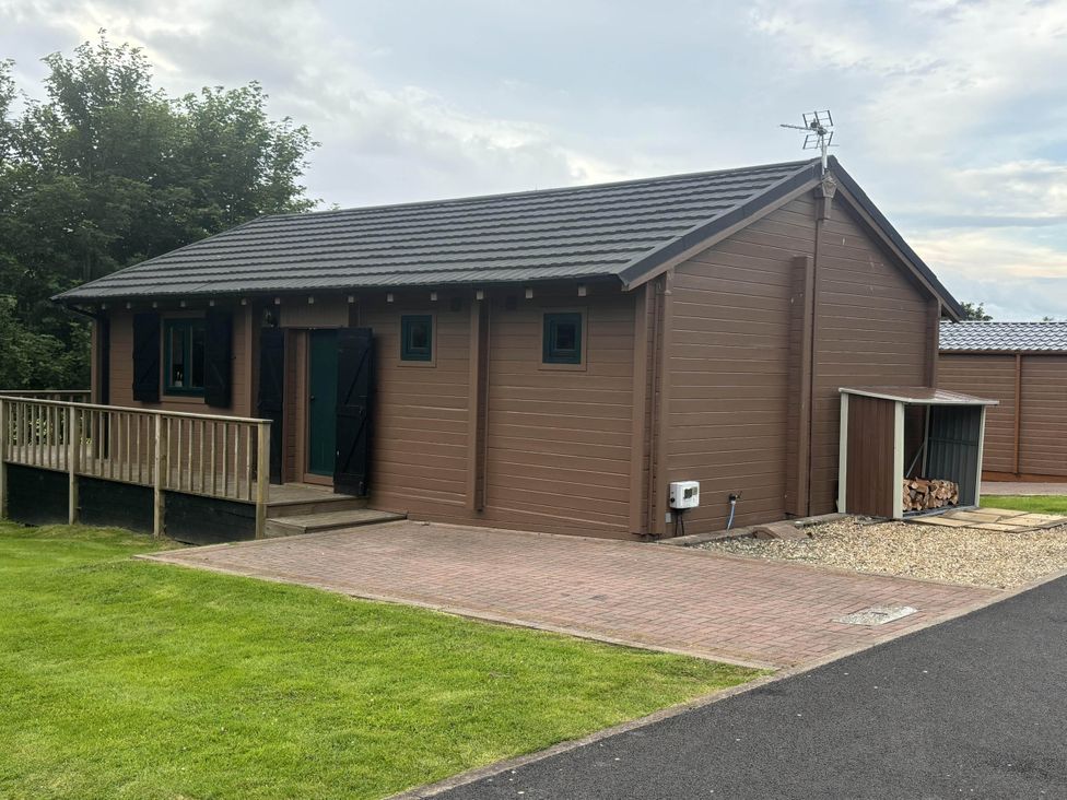 A lodge with a deck and storage shed at Pet Friendly - Lodge at Riverview Holiday Park, Mangerton near Newcastleton