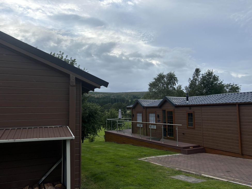 An outdoor view of a wooden cabin and deck at Pet Friendly - Lodge at Riverview Holiday Park Mangerton near Newcastleton