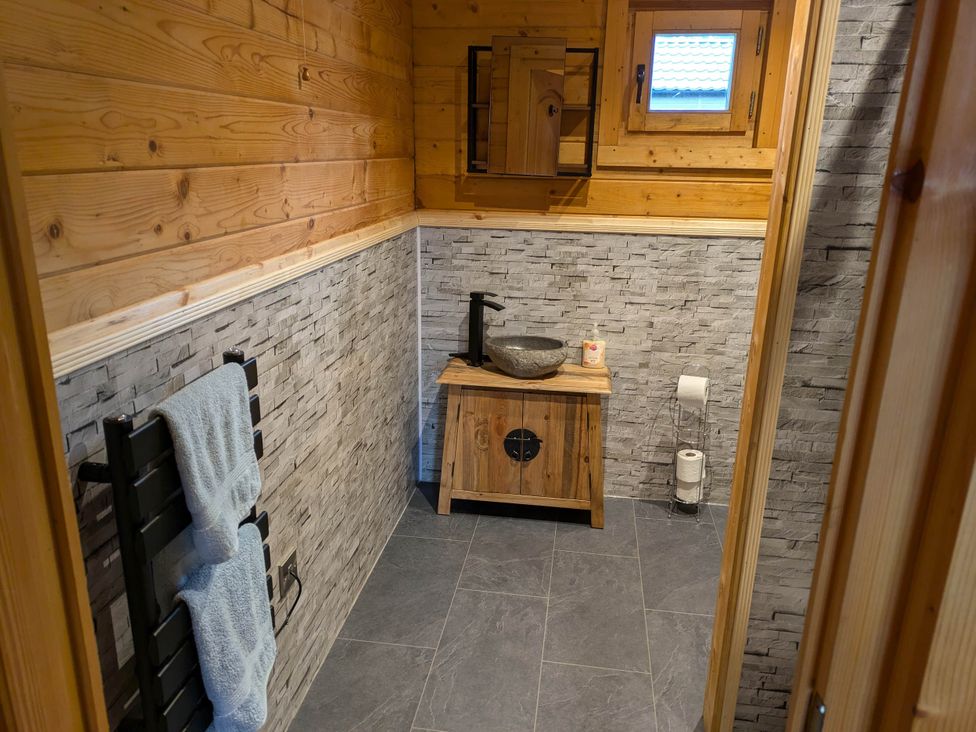A bathroom with a sink and wooden cabinet at Pet Friendly - Lodge at Riverview Holiday Park Mangerton near Newcastleton