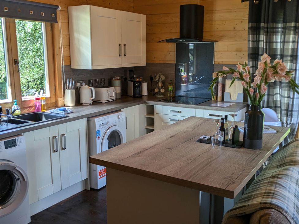 A kitchen with cabinets and appliances at Pet Friendly - Lodge at Riverview Holiday Park Mangerton near Newcastleton