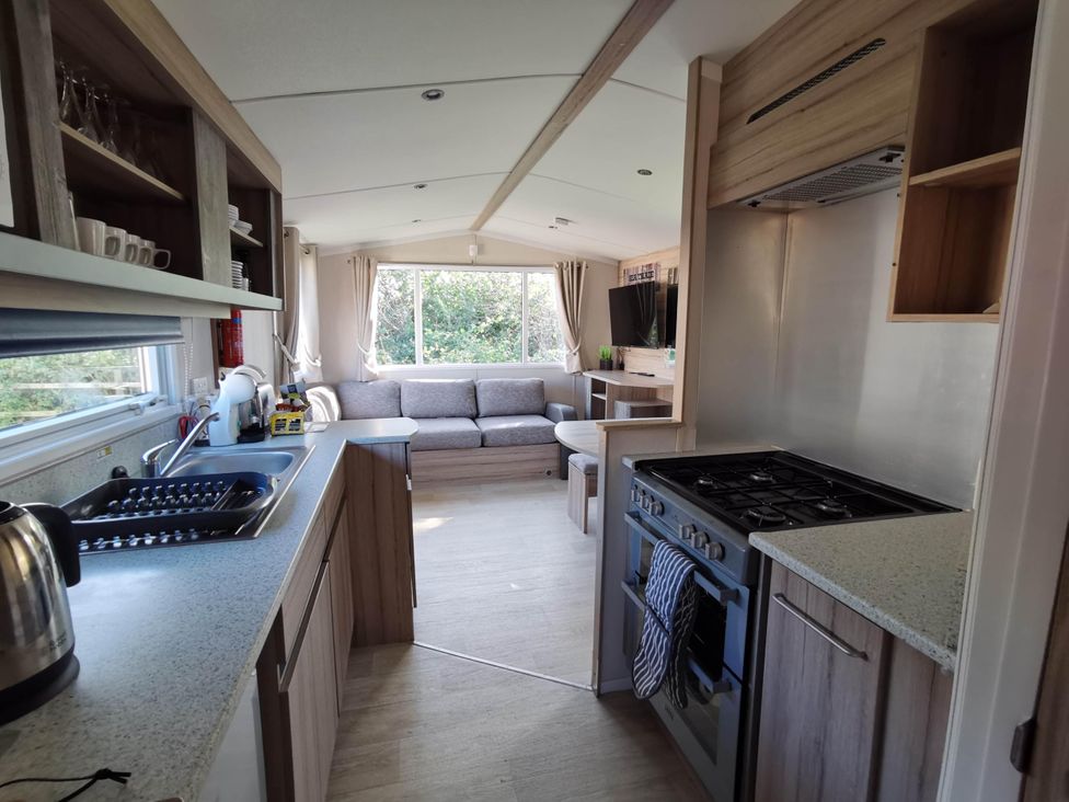 A kitchen with a cooking stove and a sofa area at 8Berth- SmartTV- CloseToBeach- FamilyFriendly in Mablethorpe