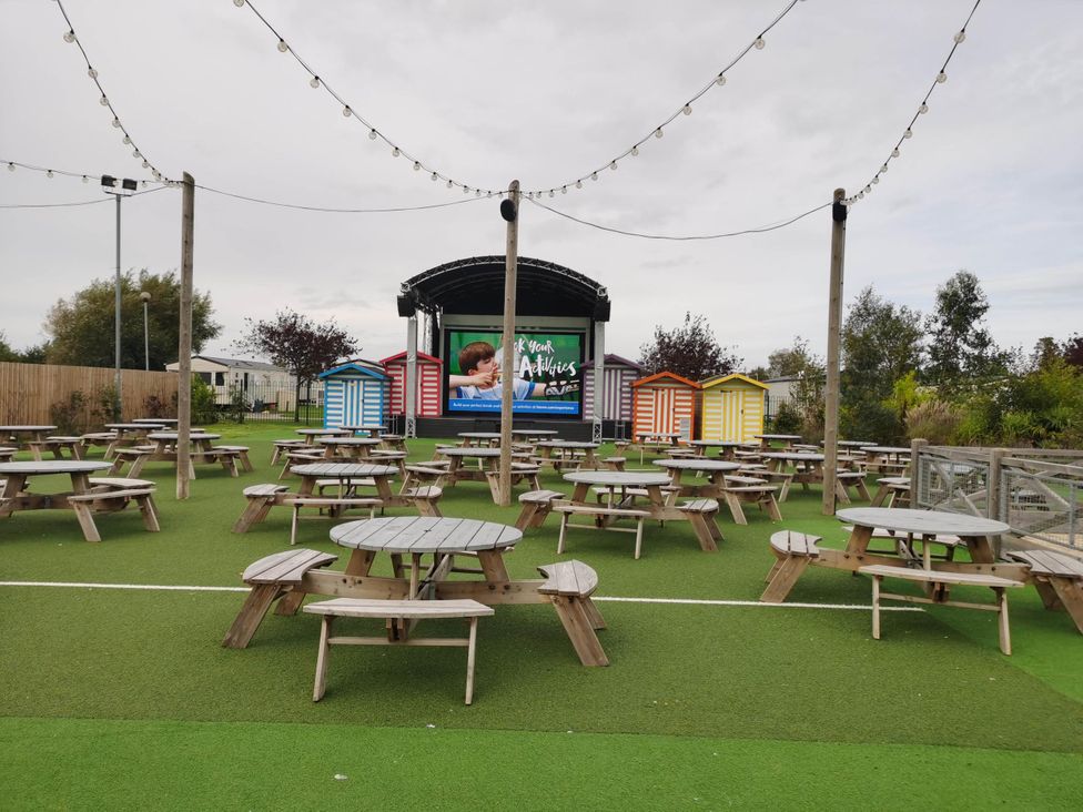 An outdoor area with picnic tables and a performance stage at 8Berth- SmartTV- CloseToBeach- FamilyFriendly in Mablethorpe
