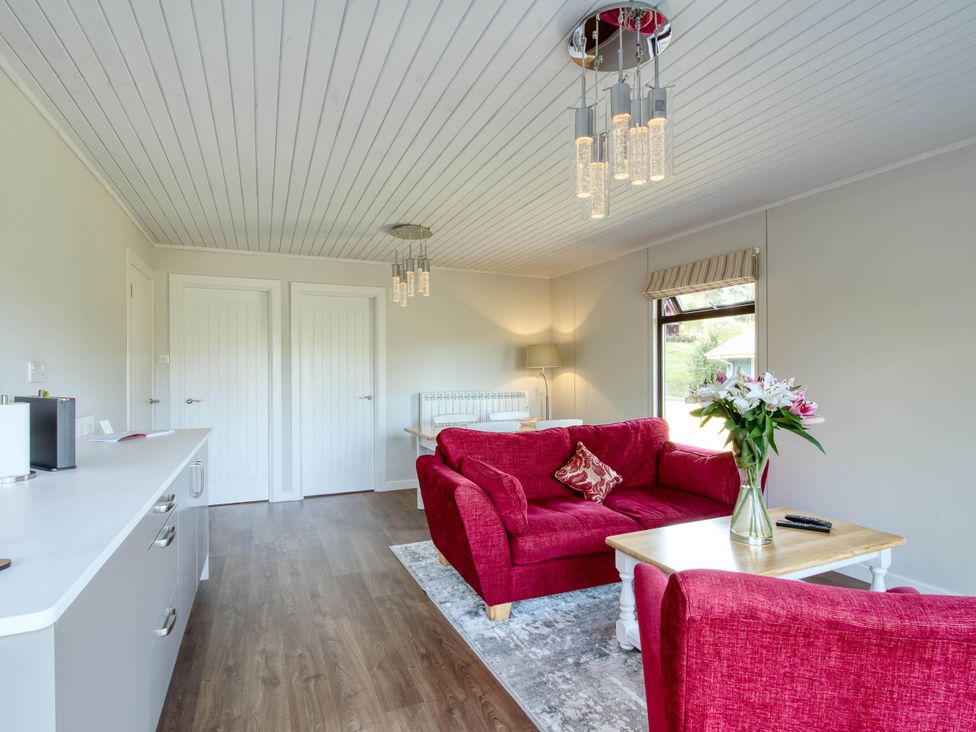 A living room with a red sofa and coffee table at 2 bedroom lodge with stunning loch, mountain views, Crianlarich