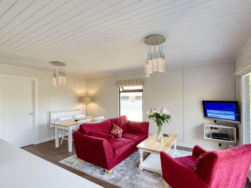 A living room with a sofa, table, and television at 2 bedroom lodge with stunning loch, mountain views, Crianlarich