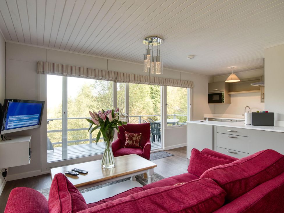 A living room with a sofa, table, and television at 2 bedroom lodge with stunning loch, mountain views, Crianlarich