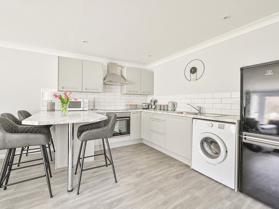 A kitchen with a washing machine and bar stools at 8Berth- SmartTV- CloseToBeach- FamilyFriendly in Millendreath near Looe