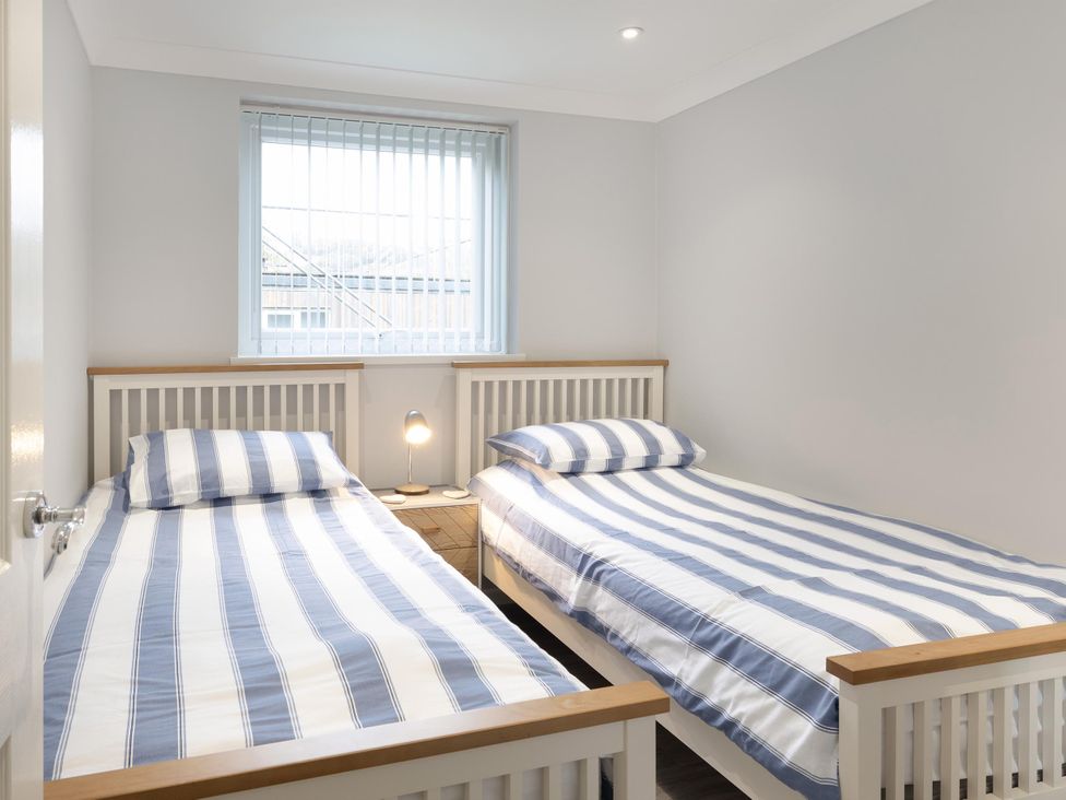 A bedroom with two single beds and a window at 8Berth- SmartTV- CloseToBeach- FamilyFriendly in Millendreath near Looe