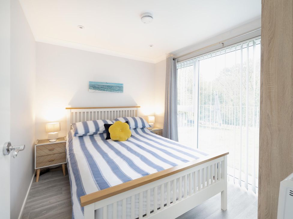 A bedroom with a bed and bedside table at 8Berth- SmartTV- CloseToBeach- FamilyFriendly in Millendreath near Looe