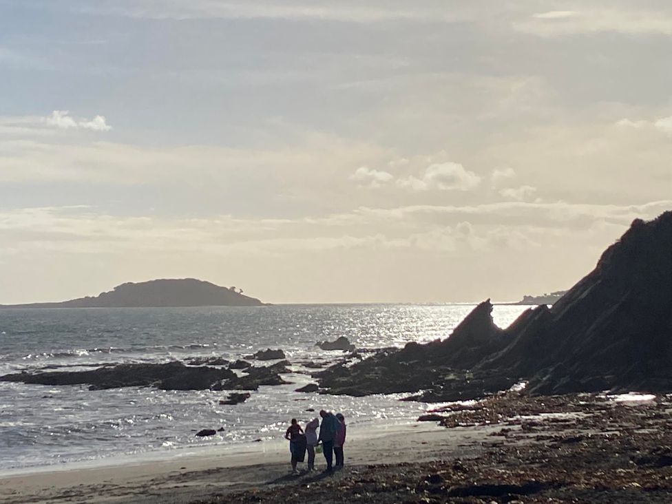 People walking on a beach with a rocky shoreline and an island in the distance at 8Berth- SmartTV- CloseToBeach- FamilyFriendly, Millendreath near Looe