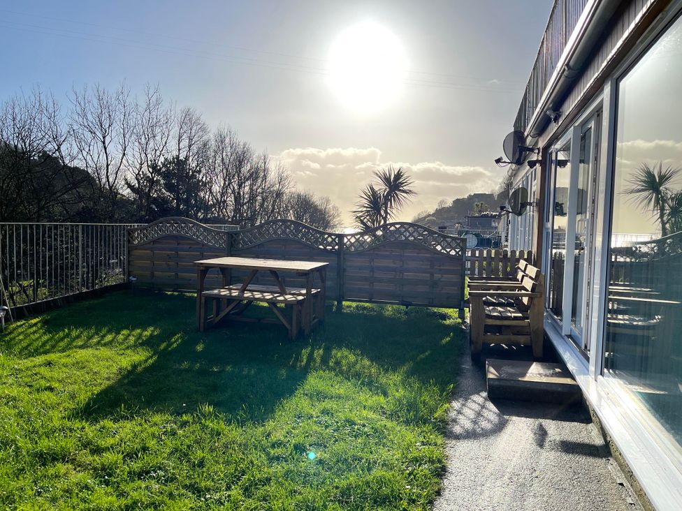 A garden with a table and bench at 8Berth- SmartTV- CloseToBeach- FamilyFriendly in Millendreath near Looe
