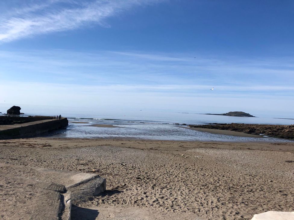 A beach with a pier and an island in the distance at 8Berth- SmartTV- CloseToBeach- FamilyFriendly in Millendreath near Looe