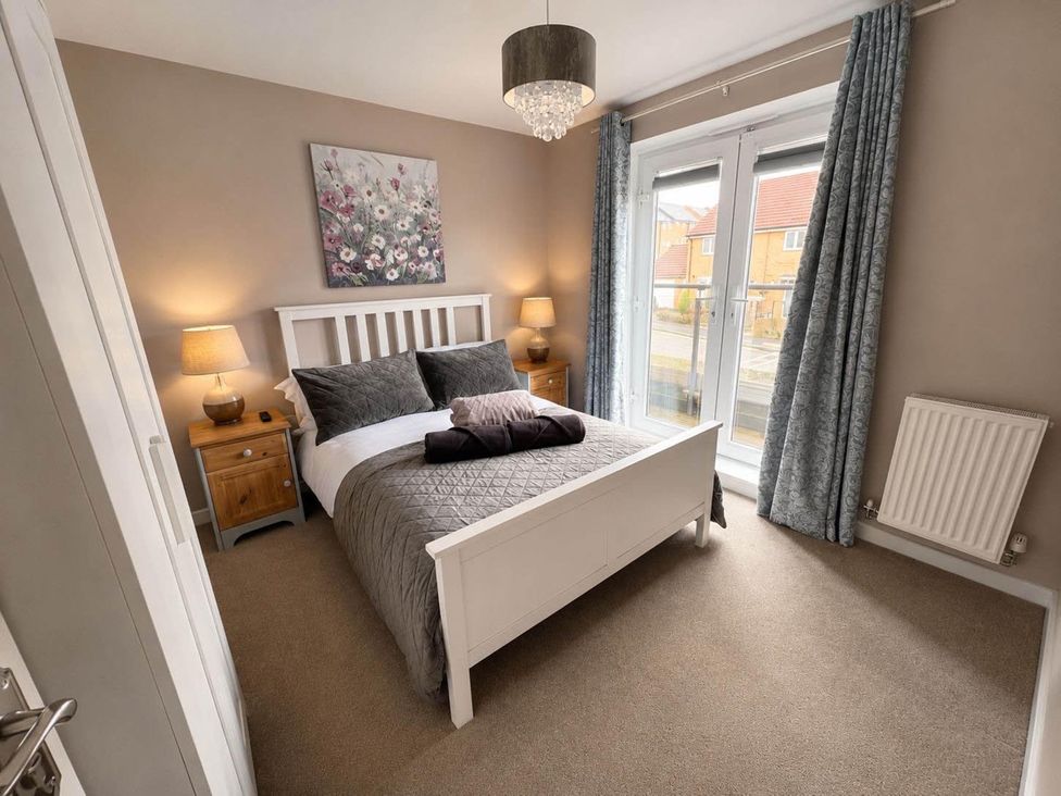 A bedroom with a bed, nightstand, and curtains at House Sleeps 12 with WiFi Bristol