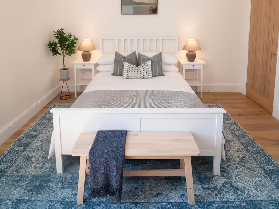 A bedroom with a bed, nightstands, and a bench at Foundry Farm Apartment in 