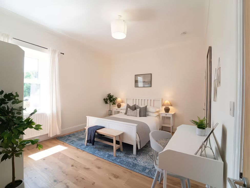 A bedroom with a bed, desk, and plant at Foundry Farm Apartment