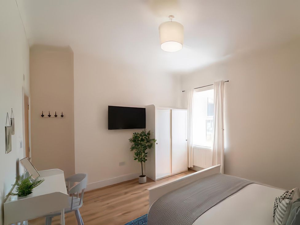 A bedroom with a bed, desk, and wardrobe at Foundry Farm Apartment